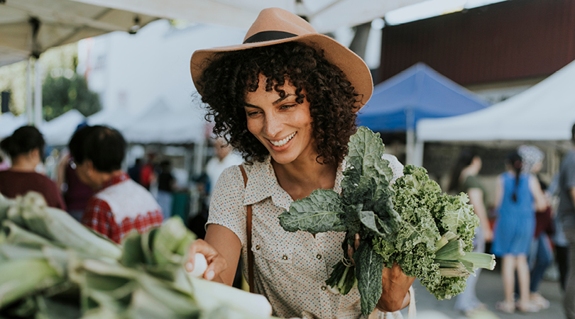 A woman at farmer's markets buying vegetables