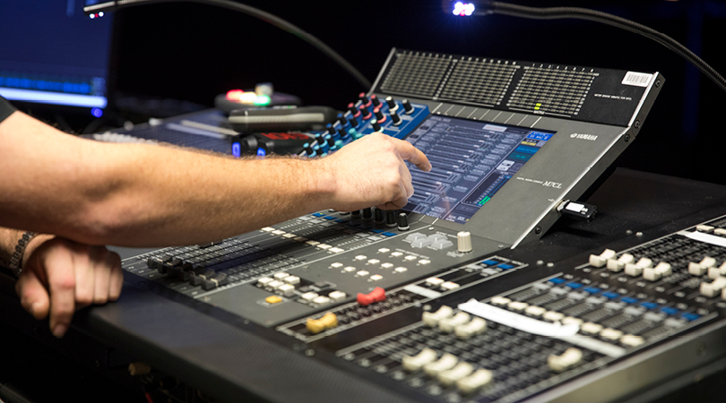 Technician's hand operating lighting and sound controls