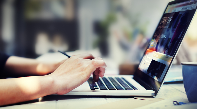 Close up photo of hands using laptop computer