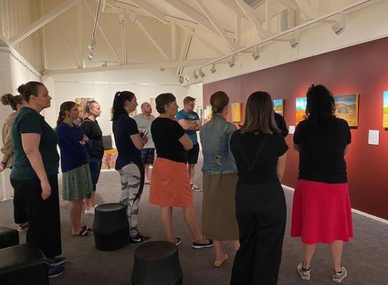 Large group of people standing in art gallery looking at the same artwork