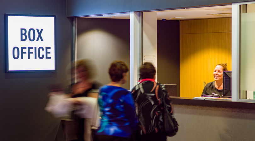 Customers lined up at the Box Office; sign reads 