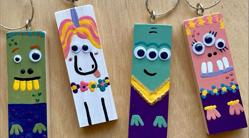 wooden hanging decorations with painted alien faces on them