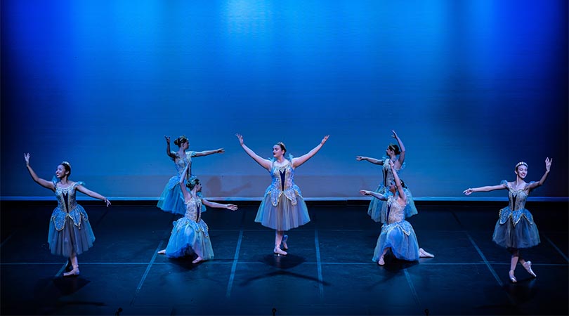7 ballet dancers on stage with blue stage lighting