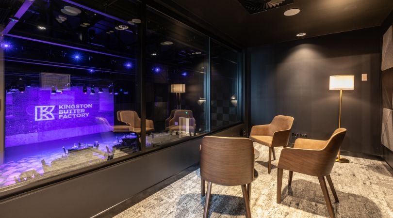 Hush Room with chairs, lamp and glass window that overlooks the Butterbox Theatre stage.