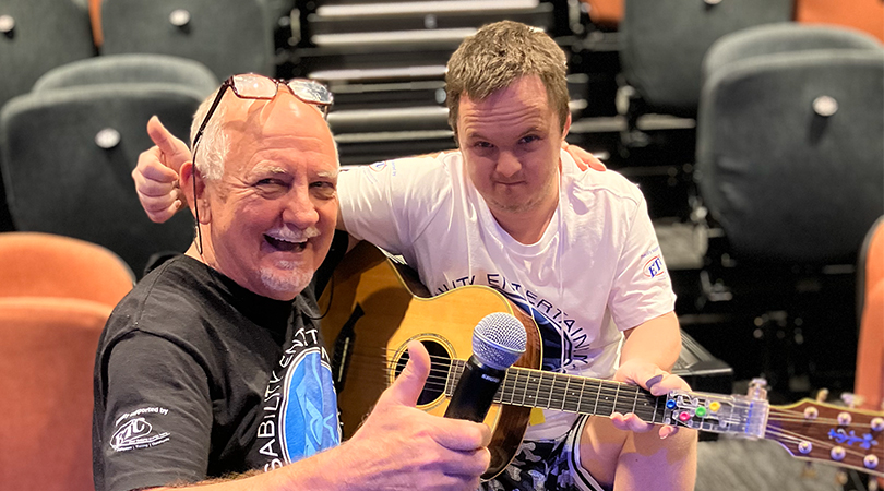 DEAI teacher and student showing thumbs up whilst learning a guitar